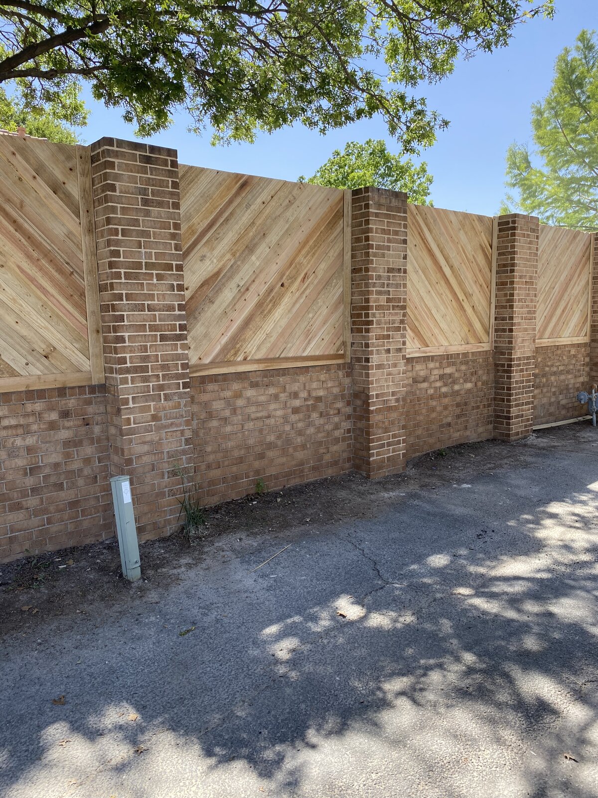 Custom diagonal cedar privacy fence with brick pillars in Bushland, TX