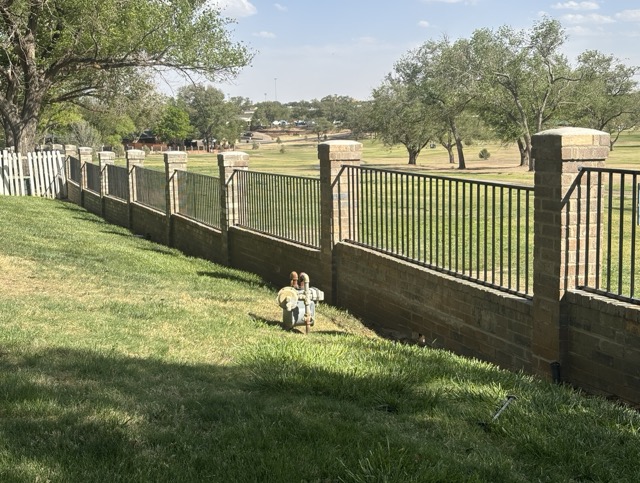 Ornamental iron fence with brick columns and park view